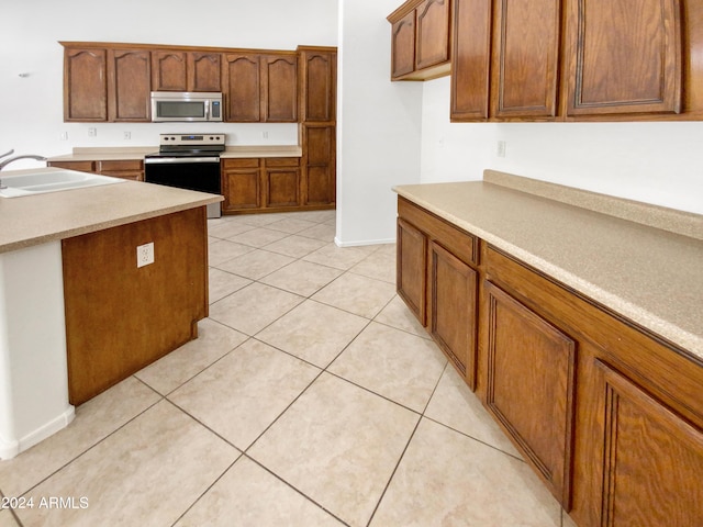 kitchen with light tile patterned floors, stainless steel appliances, and sink