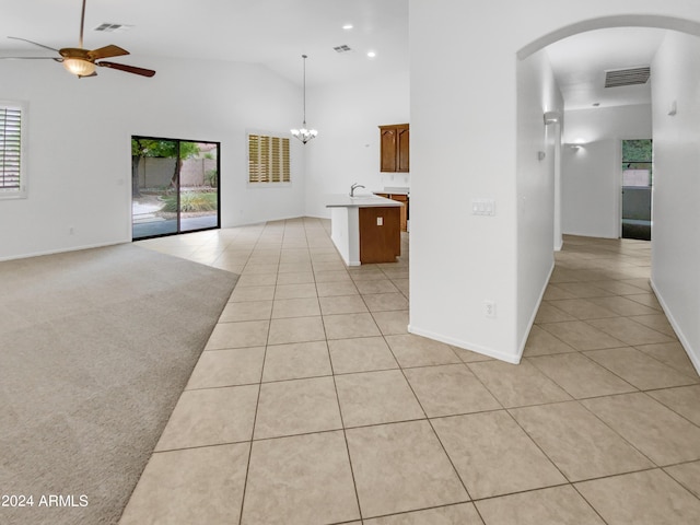 interior space featuring light tile patterned floors, ceiling fan with notable chandelier, high vaulted ceiling, and sink