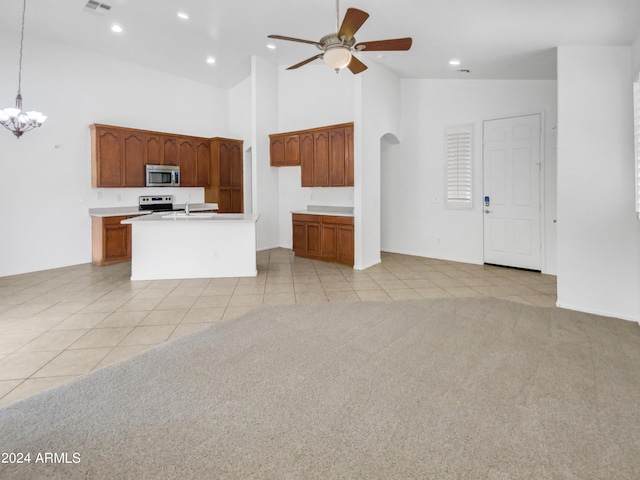 unfurnished living room featuring ceiling fan with notable chandelier, light colored carpet, and high vaulted ceiling