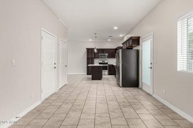2000 N 36th St Unit 29, Phoenix, AZ 85008 - kitchen with appliances with stainless steel finishes, a center island, dark brown cabinetry, light tile patterned floors, and baseboards