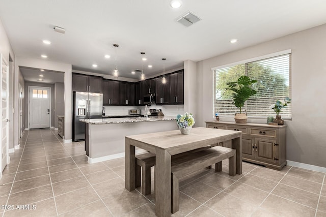 19920 W Monterosa St, Litchfield Park, AZ 85340 - kitchen featuring light stone counters, light tile patterned flooring, stainless steel appliances, visible vents, and pendant lighting
