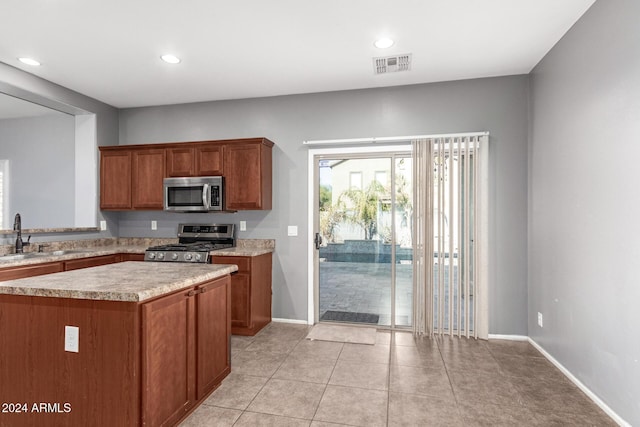 kitchen featuring light tile patterned floors, a center island, stainless steel appliances, and sink