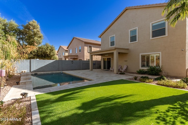 rear view of property featuring a patio, a fenced in pool, and a lawn