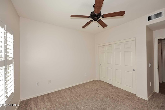 unfurnished bedroom featuring multiple windows, ceiling fan, light colored carpet, and a closet