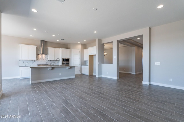 kitchen featuring decorative light fixtures, tasteful backsplash, a kitchen island with sink, and white cabinetry