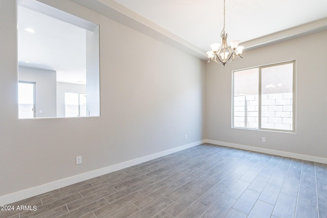 empty room featuring an inviting chandelier and hardwood / wood-style flooring