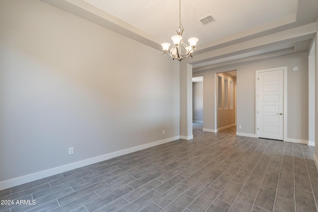 empty room with a chandelier, a raised ceiling, and dark hardwood / wood-style flooring