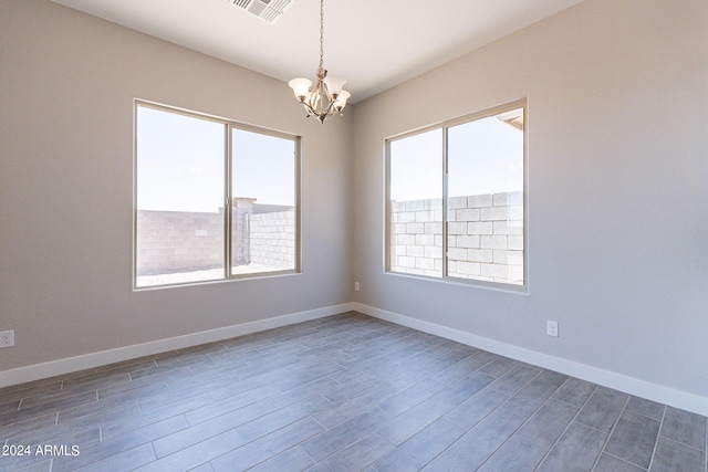 empty room featuring a notable chandelier and dark wood-type flooring