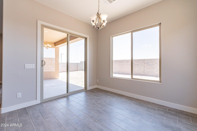 spare room with dark hardwood / wood-style floors, a healthy amount of sunlight, and a chandelier