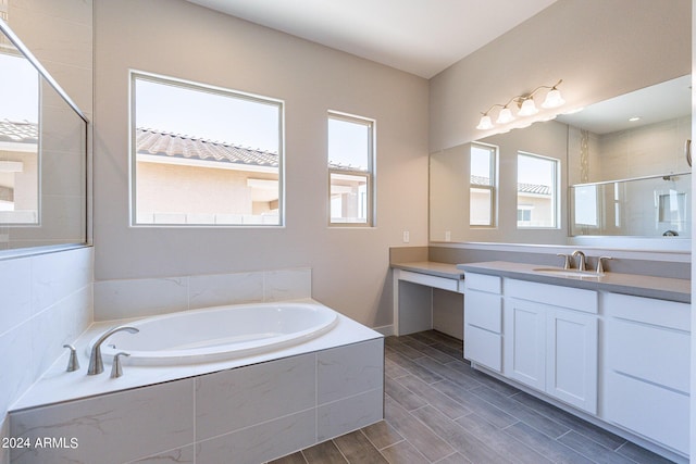 bathroom with a relaxing tiled bath and vanity with extensive cabinet space