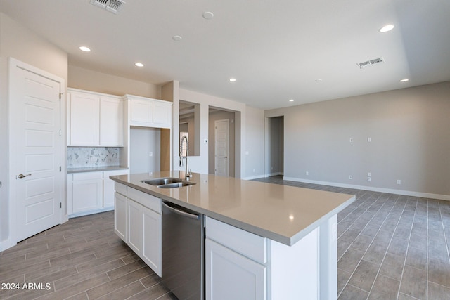 kitchen featuring dishwasher, tasteful backsplash, white cabinetry, an island with sink, and sink