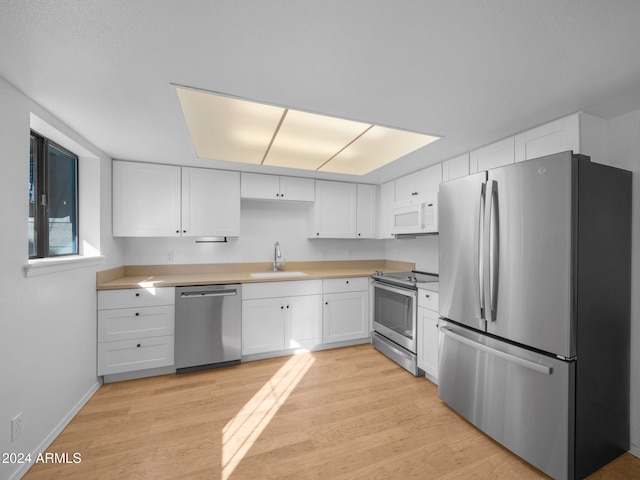 kitchen with white cabinets, light hardwood / wood-style floors, sink, and appliances with stainless steel finishes