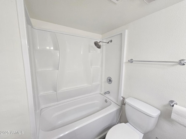 bathroom with toilet and a textured wall