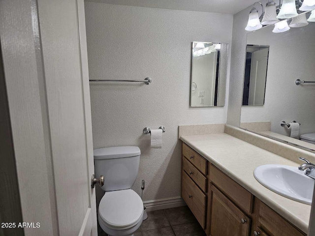 bathroom with toilet, baseboards, tile patterned flooring, and vanity