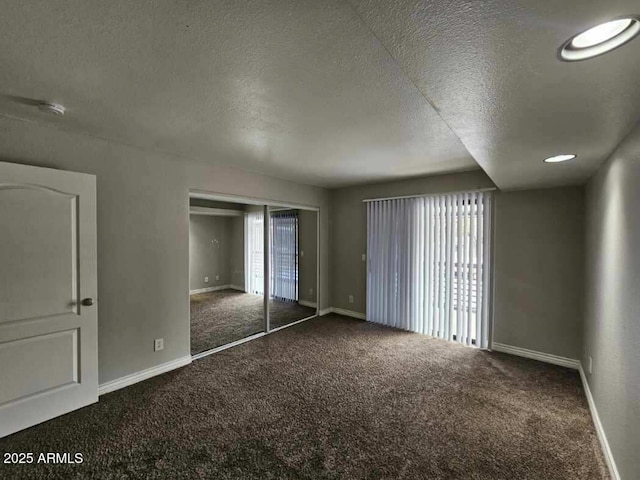 unfurnished bedroom with a textured ceiling, carpet floors, and baseboards