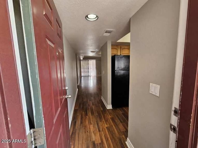 hall featuring dark wood finished floors, visible vents, baseboards, and a textured ceiling