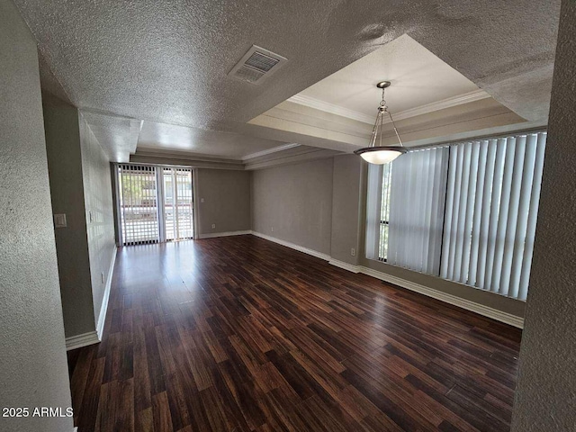unfurnished room featuring wood finished floors, crown molding, a textured ceiling, visible vents, and baseboards