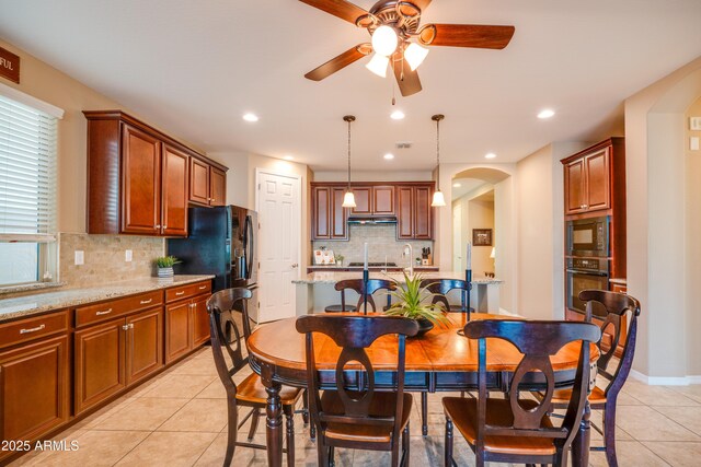 20742 E Mockingbird Dr, Queen Creek, AZ 85142 - kitchen featuring light tile patterned floors, arched walkways, decorative backsplash, black appliances, and ceiling fan