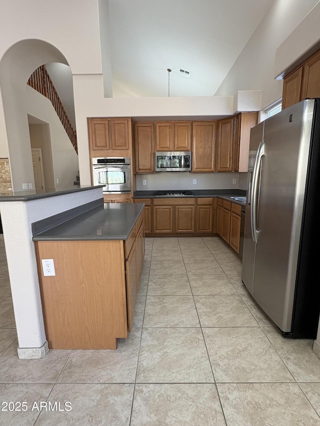 33512 N 24th Ln, Phoenix, AZ 85085 - kitchen featuring stainless steel appliances, dark countertops, brown cabinetry, high vaulted ceiling, and light tile patterned flooring