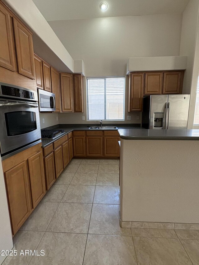 33512 N 24th Ln, Phoenix, AZ 85085 - kitchen featuring appliances with stainless steel finishes, a sink, dark countertops, brown cabinetry, and light tile patterned floors