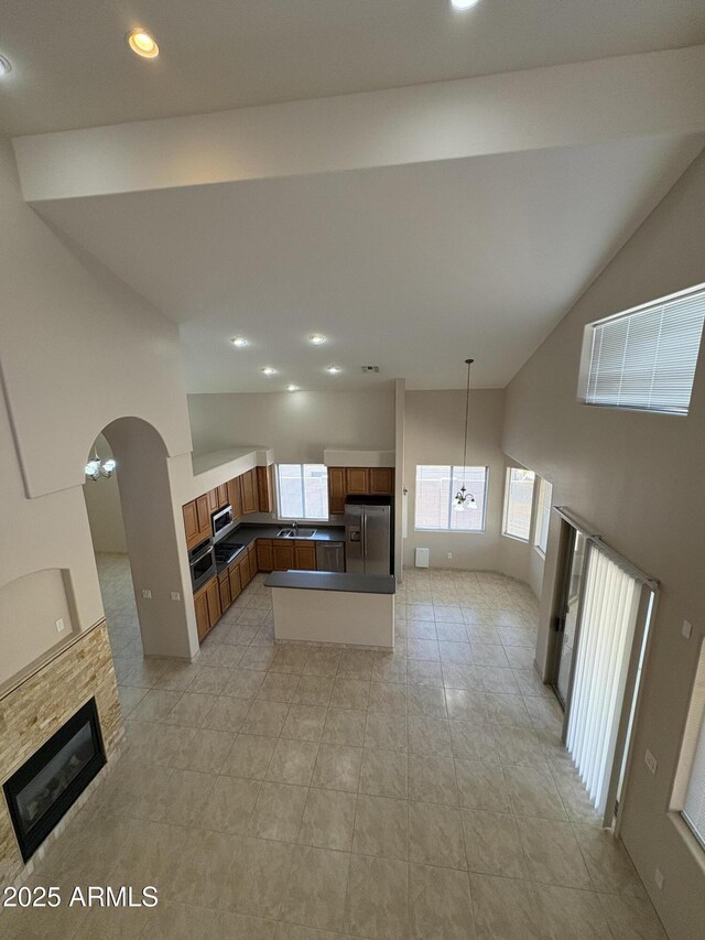 33512 N 24th Ln, Phoenix, AZ 85085 - kitchen featuring stainless steel fridge with ice dispenser, healthy amount of natural light, brown cabinetry, a multi sided fireplace, and high vaulted ceiling