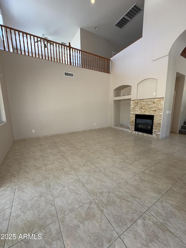 33512 N 24th Ln, Phoenix, AZ 85085 - unfurnished living room with a high ceiling, built in shelves, a tiled fireplace, stairway, and tile patterned flooring