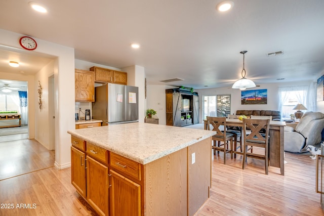 kitchen featuring a kitchen island, light hardwood / wood-style floors, stainless steel fridge, and plenty of natural light