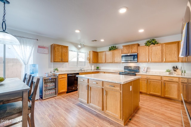 kitchen with pendant lighting, black appliances, a center island, sink, and light hardwood / wood-style flooring