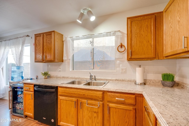 kitchen with decorative backsplash, sink, black dishwasher, and light wood-type flooring