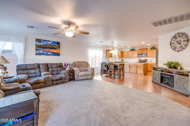 living room featuring light hardwood / wood-style floors, ceiling fan, and plenty of natural light