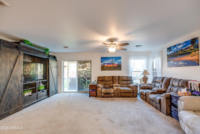 carpeted living room featuring ceiling fan and a barn door