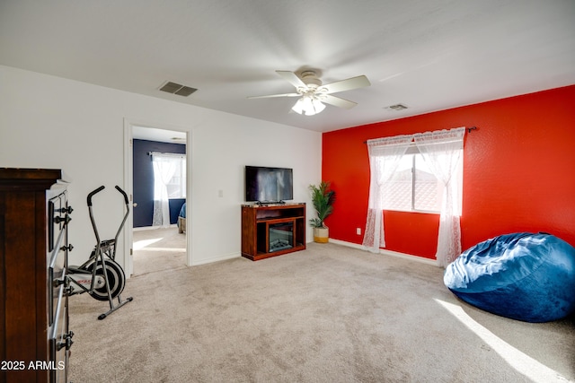 living area featuring ceiling fan, plenty of natural light, and carpet