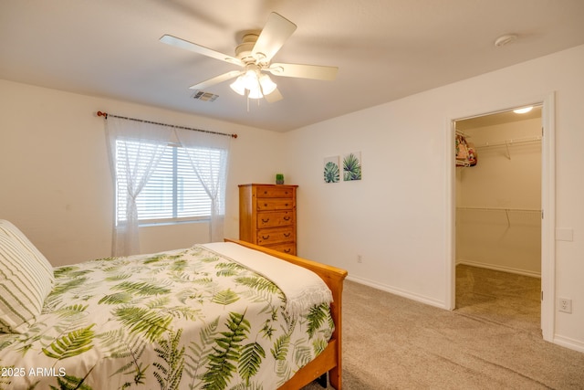 bedroom featuring a walk in closet, ceiling fan, light carpet, and a closet