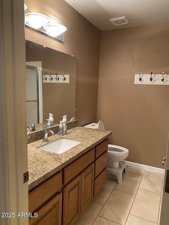 bathroom featuring tile patterned floors, a shower with door, toilet, vanity, and visible vents