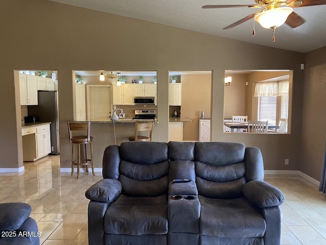 living area featuring light tile patterned floors, a ceiling fan, high vaulted ceiling, and baseboards