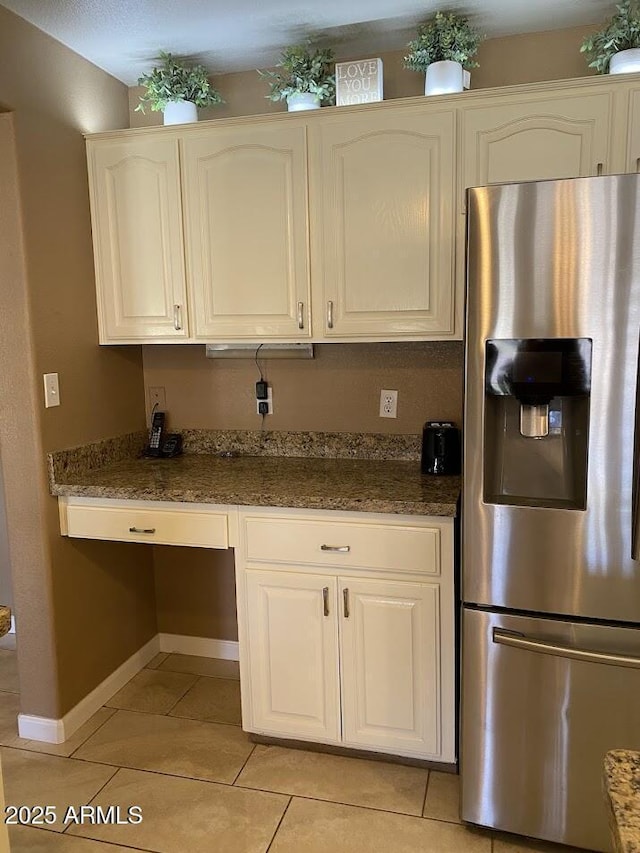 kitchen with light tile patterned floors, white cabinetry, baseboards, built in study area, and stainless steel refrigerator with ice dispenser