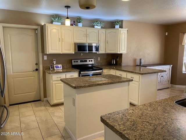 kitchen with dark stone countertops, appliances with stainless steel finishes, a center island, pendant lighting, and a peninsula