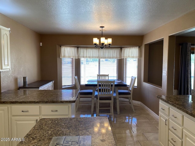 dining space featuring baseboards, an inviting chandelier, a textured ceiling, and light tile patterned flooring