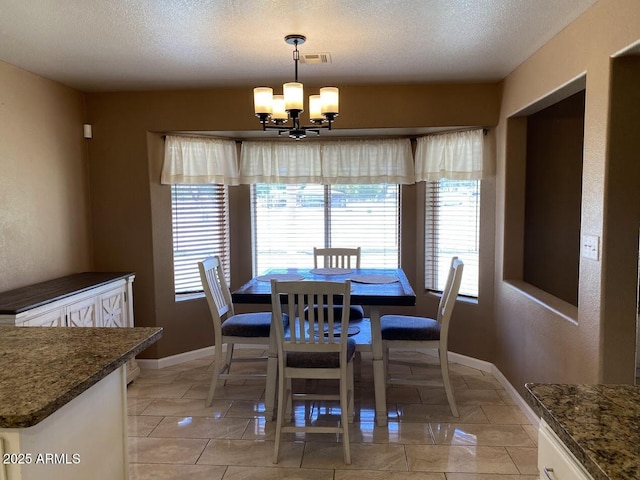 dining area with light tile patterned flooring, a notable chandelier, visible vents, baseboards, and a textured ceiling