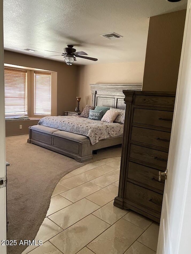 bedroom featuring light colored carpet, visible vents, ceiling fan, and a textured ceiling