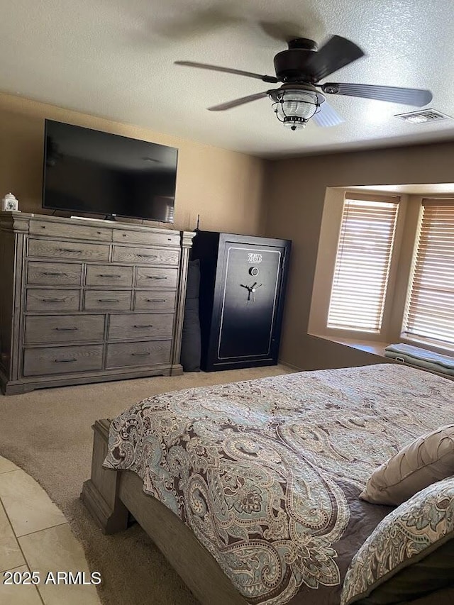 bedroom with light colored carpet, light tile patterned floors, visible vents, a ceiling fan, and a textured ceiling