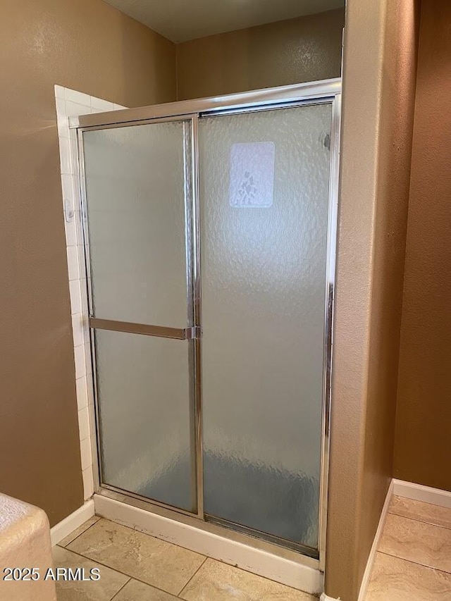bathroom with baseboards, a stall shower, and tile patterned flooring