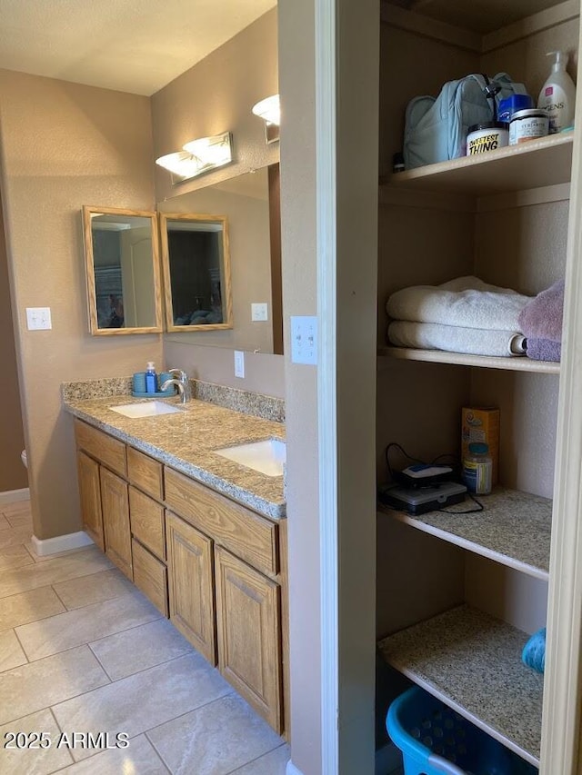 full bathroom featuring tile patterned flooring, a sink, double vanity, and baseboards