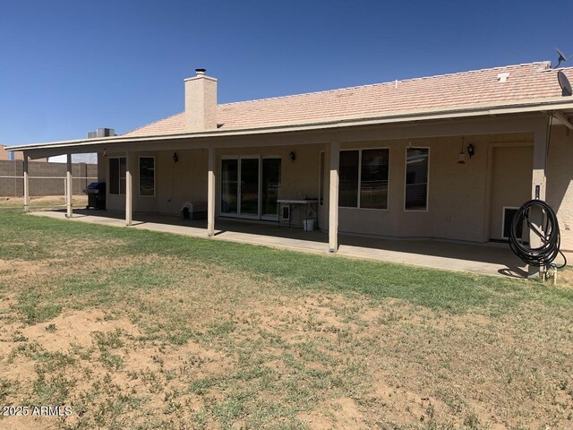 rear view of property with a patio, a lawn, and a chimney