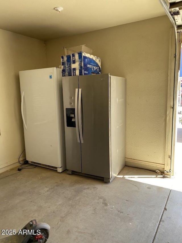 interior space featuring stainless steel refrigerator with ice dispenser, unfinished concrete floors, and freestanding refrigerator