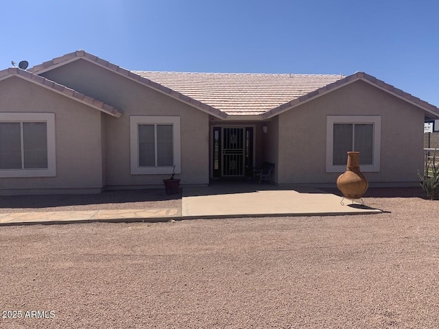view of front of house with a patio, stucco siding, and a tile roof