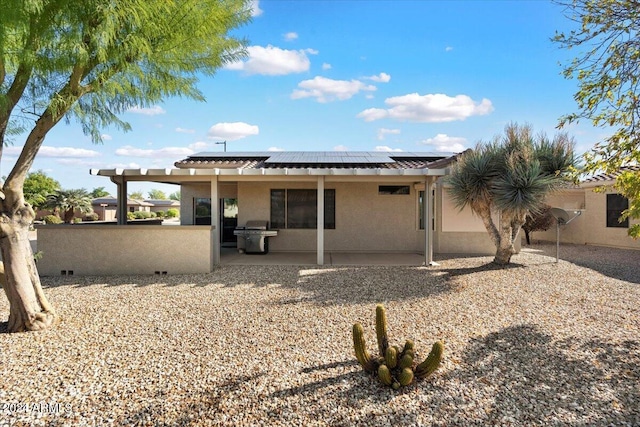 rear view of property with a patio area and solar panels