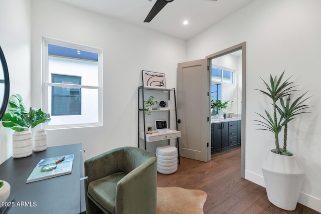 living area featuring ceiling fan and dark hardwood / wood-style flooring