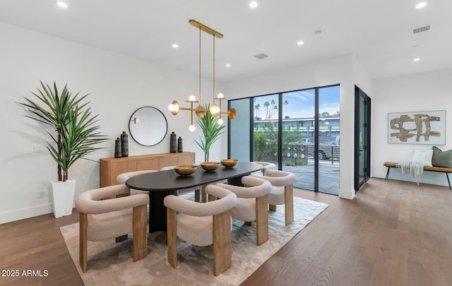 dining space featuring wood-type flooring and an inviting chandelier