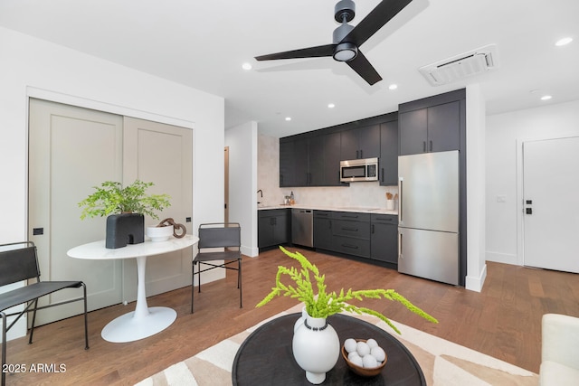 kitchen with ceiling fan, sink, dark wood-type flooring, stainless steel appliances, and decorative backsplash